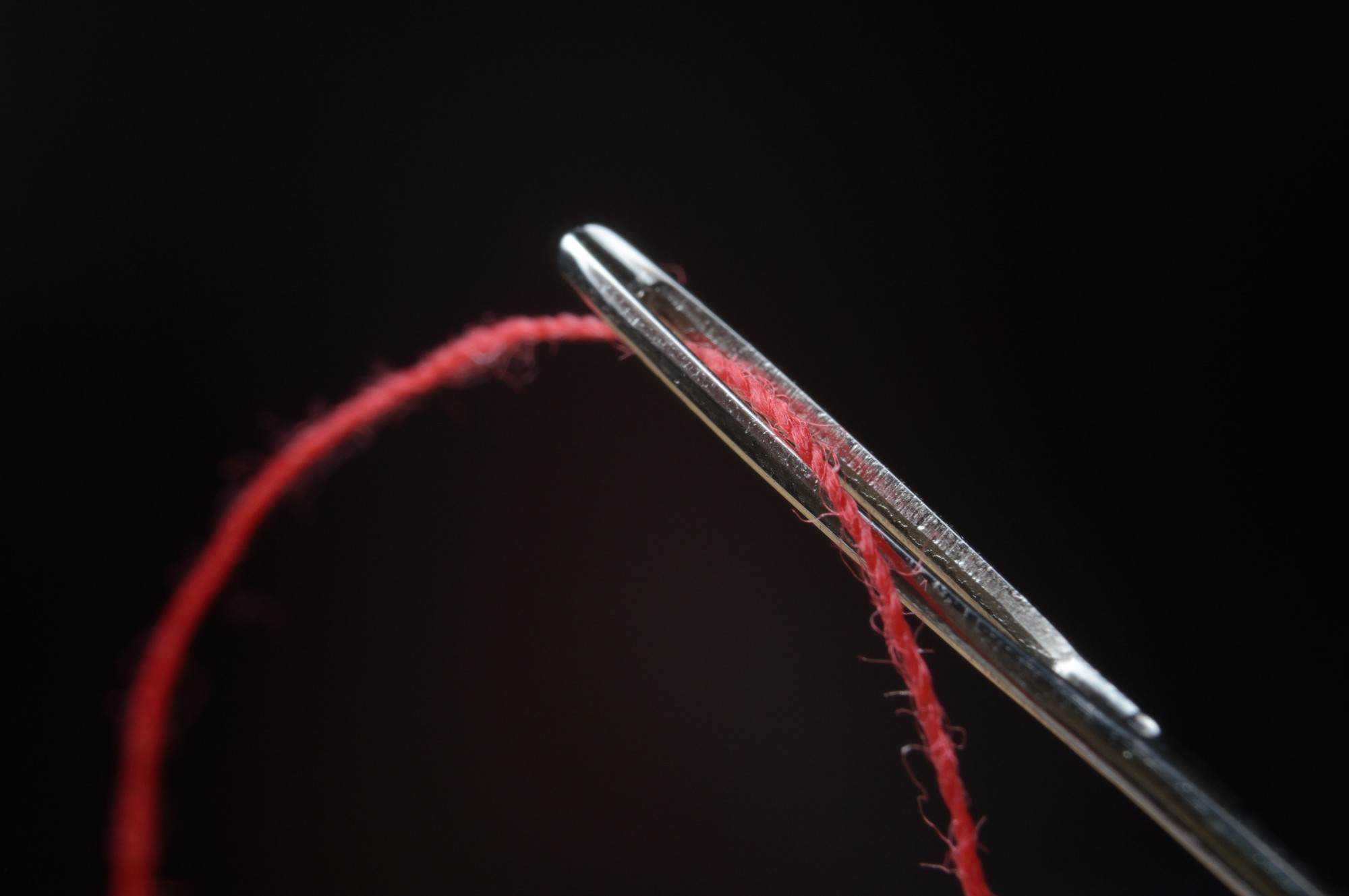 Mano che guida ago su tessuto tecnico con luci al neon
